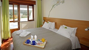A hotel room with a bed, breakfast tray, and a window with curtains. - Sintra Sol - Apartamentos Turisticos (Sintra)