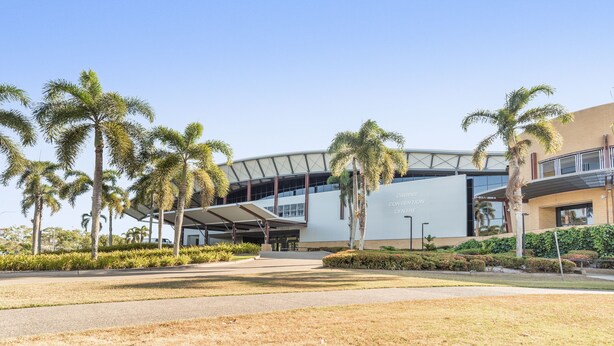 A modern building with a curved roof and a sign that reads "CAIRNS CONVENTION CENTER."