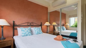 A hotel room with a large bed, two bedside lamps, a hat, and a magazine on the bed.