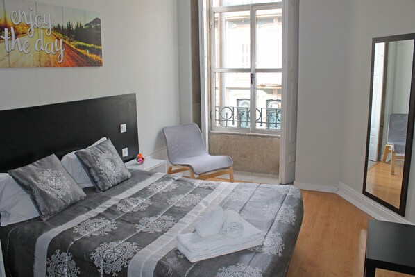 Ein Schlafzimmer mit Bett, Stuhl, Fenster und Spiegel.