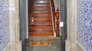A staircase with a wooden handrail and a doormat at the bottom. - Lunar Guest House (Porto)