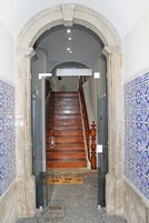 Uma escada com corrimão de madeira e um tapete na base.
