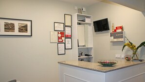 A reception area with a counter, framed certificates, a television, and a plant. - Lunar Guest House (Porto)