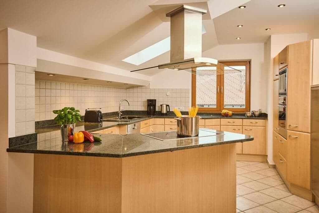 Une cuisine moderne dotée d’un îlot central, de meubles en bois et d’une fenêtre qui laisse entrer la lumière naturelle.