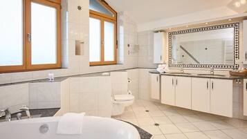 Een moderne badkamer met een vrijstaand bad, een toilet en een wastafel met een grote spiegel.