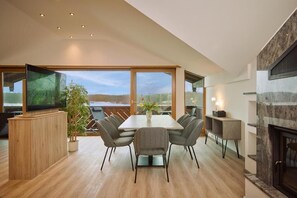 A modern dining area with a large table, chairs, a television, and a fireplace. - Aktiv- und Wellnesshotel Seeblick (Bad Endorf)