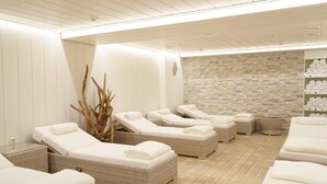 A spa area with multiple sun loungers, a stone wall, and a white wooden ceiling. - Aktiv- und Wellnesshotel Seeblick (Bad Endorf)