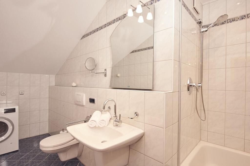 Een moderne badkamer met een wastafel, spiegel, handdoekhouder en douche.