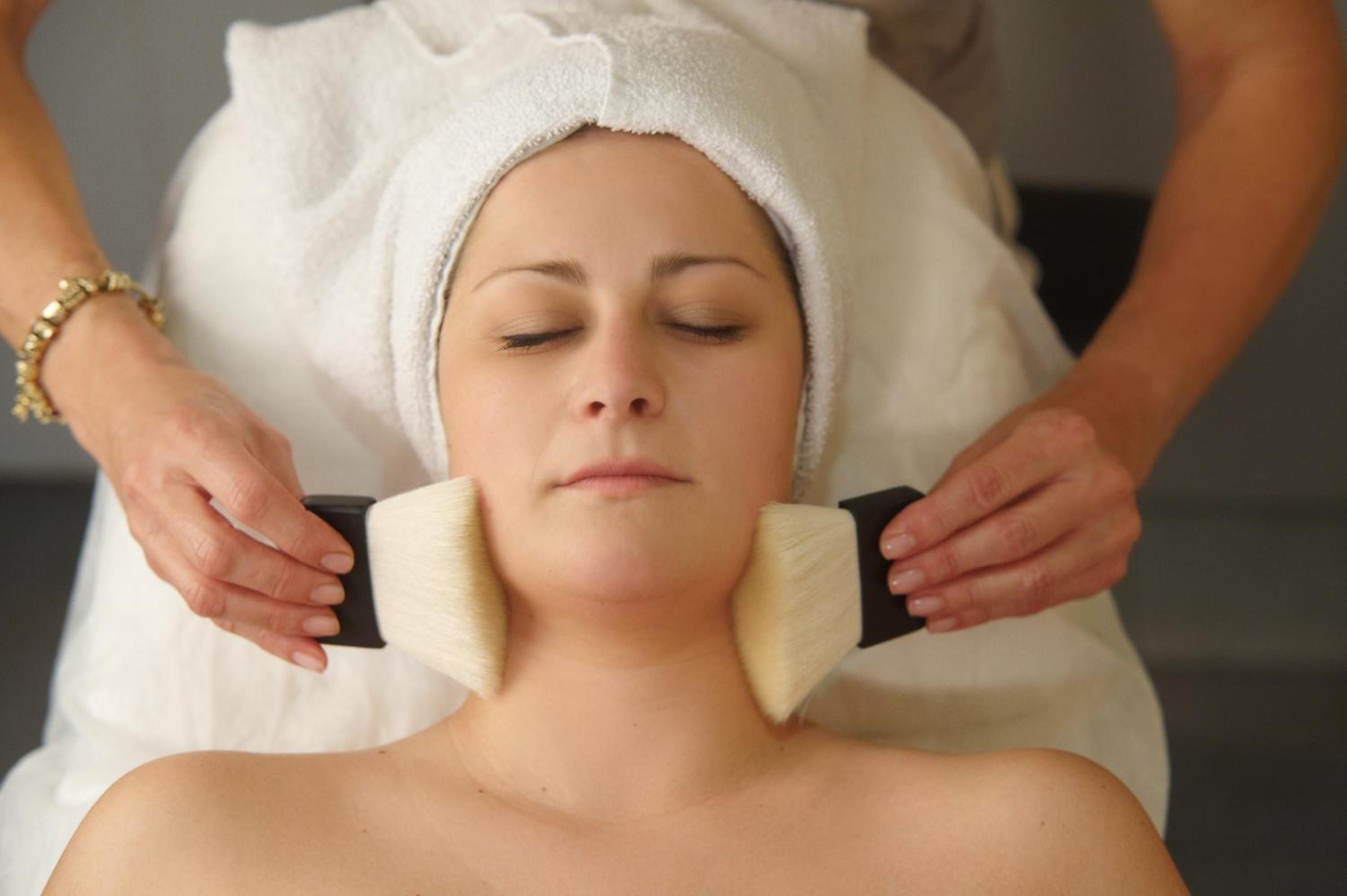A person receiving a facial treatment with a towel wrapped around their head.