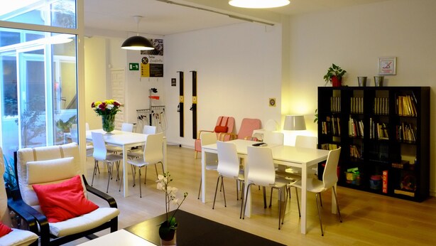 Un interno moderno con zona pranzo, sedie bianche, un tavolo e una libreria.