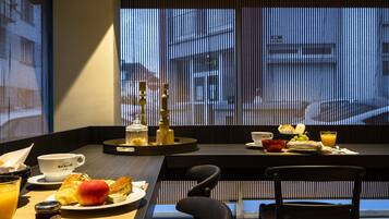 A breakfast setting with a table, chairs, and a view of the street through blinds.