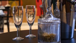 Een tafel met een champagnefles, twee wijnglazen en een kristallen karaf.