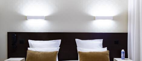 Una habitación de hotel con una cama grande, dos mesitas de noche y un teléfono en la pared.