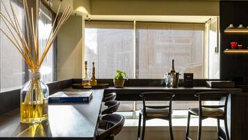 Una cocina moderna con una isla central, taburetes de bar, una botella de vino y una planta en maceta.