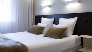 Een moderne hotelkamer met een opgemaakt bed, twee nachtkastjes en een wandlamp.