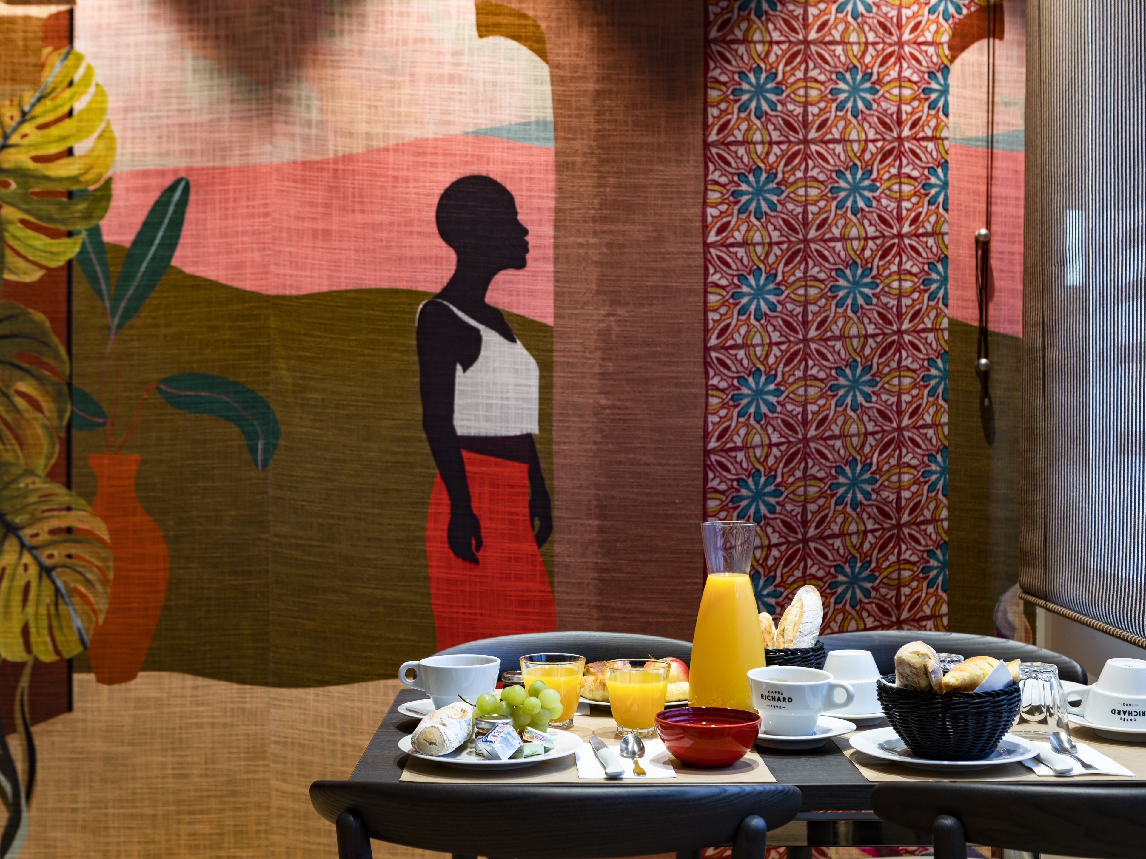 A breakfast table with plates of food, a glass of orange juice, and a cup.