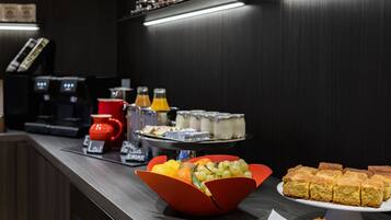 Un bufé de desayuno con diversos alimentos, máquinas de café y condimentos.