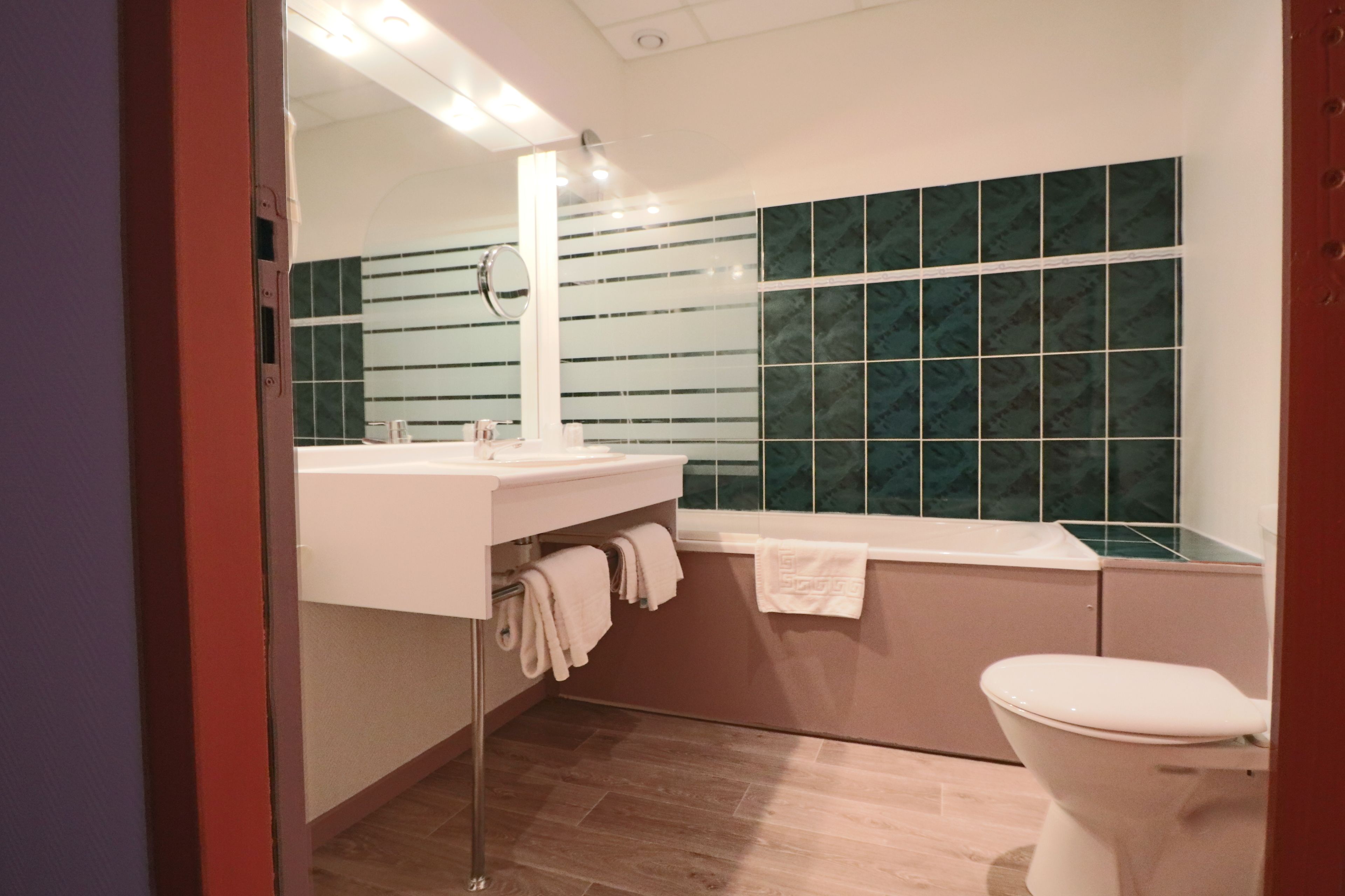 A modern bathroom with a white sink, a mirror, a bathtub, and a toilet.