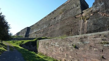 A stone wall with a pathway leading to a large, rectangular structure.