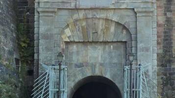 Un arc en pierre surmonté d’une plaque, qui mène à un tunnel.