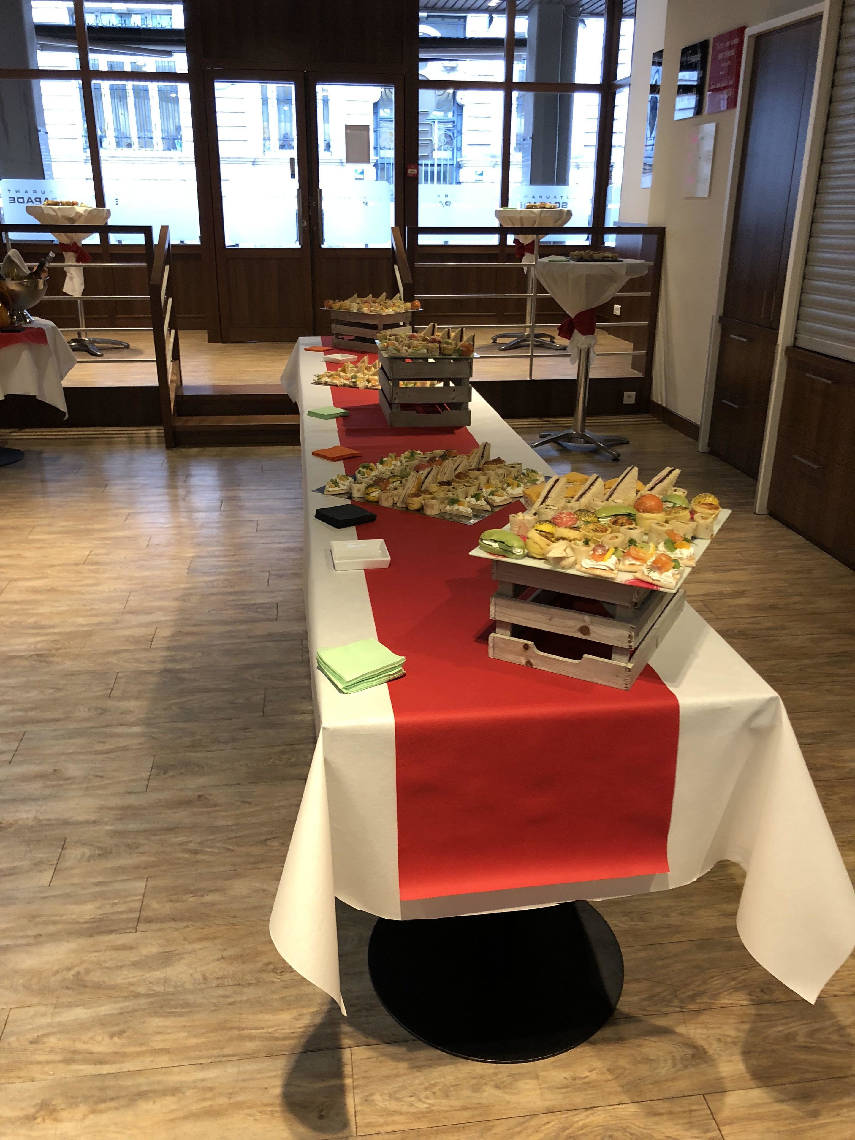A buffet table with various food items, set up in a room with large windows and wooden flooring.
