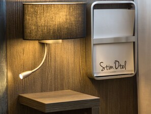 A wall-mounted lamp and a minibar with the name 'Stim Dotel'. - Citotel Stim'otel (Agen)
