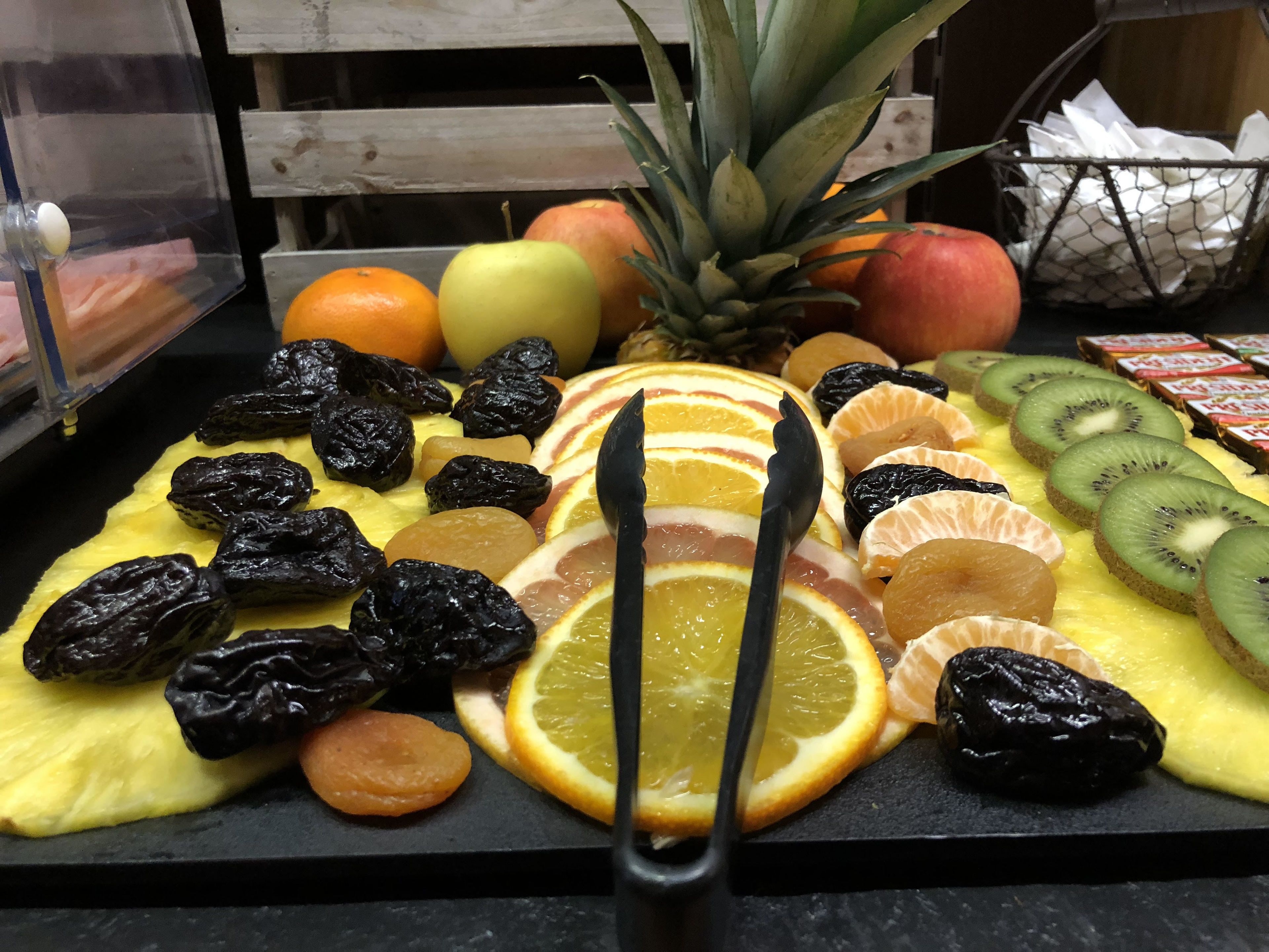Uma tábua de frutas com diversas frutas frescas e secas.