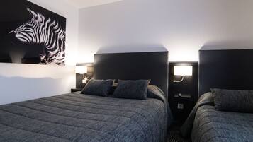 Quarto de hotel com duas camas, um mural de zebras e luminárias fixadas na parede.
