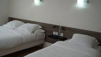 Two single beds with white linens, a wooden headboard, and two wall-mounted light fixtures.
