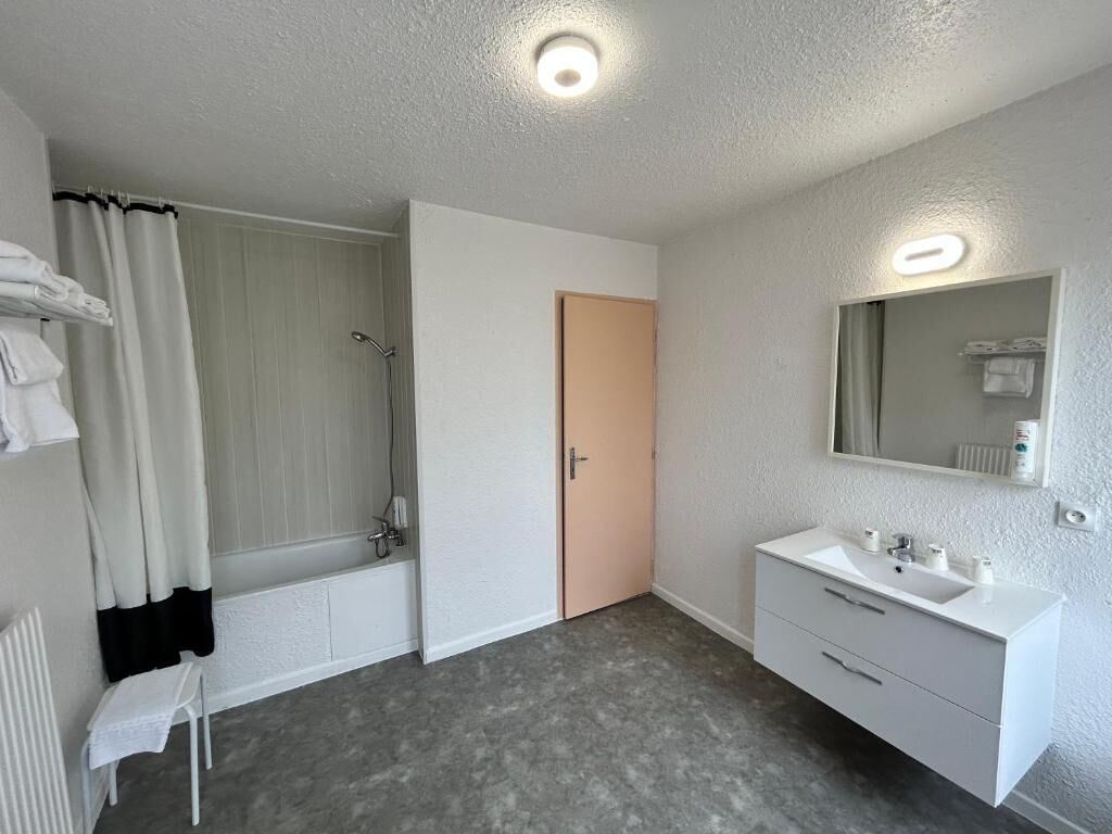A bathroom with a bathtub, a shower, a sink, and a mirror.