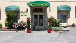 The exterior of Hotel du Tigue with a classic facade, a green awning, and potted plants in front. - Citotel Du Tigre (Verdun)