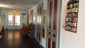 A hallway with a bar area, a bookshelf with travel books, and a door leading to another room. - Citotel Du Tigre (Verdun)