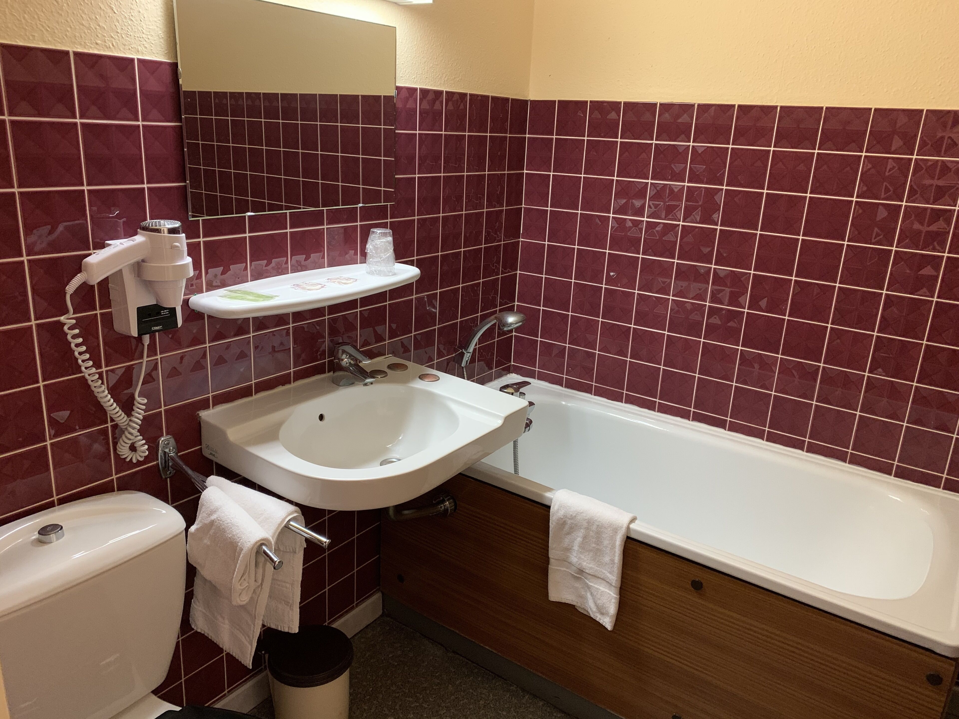 Een badkamer met een witte wastafel, een badkuip, een toilet en een spiegel.