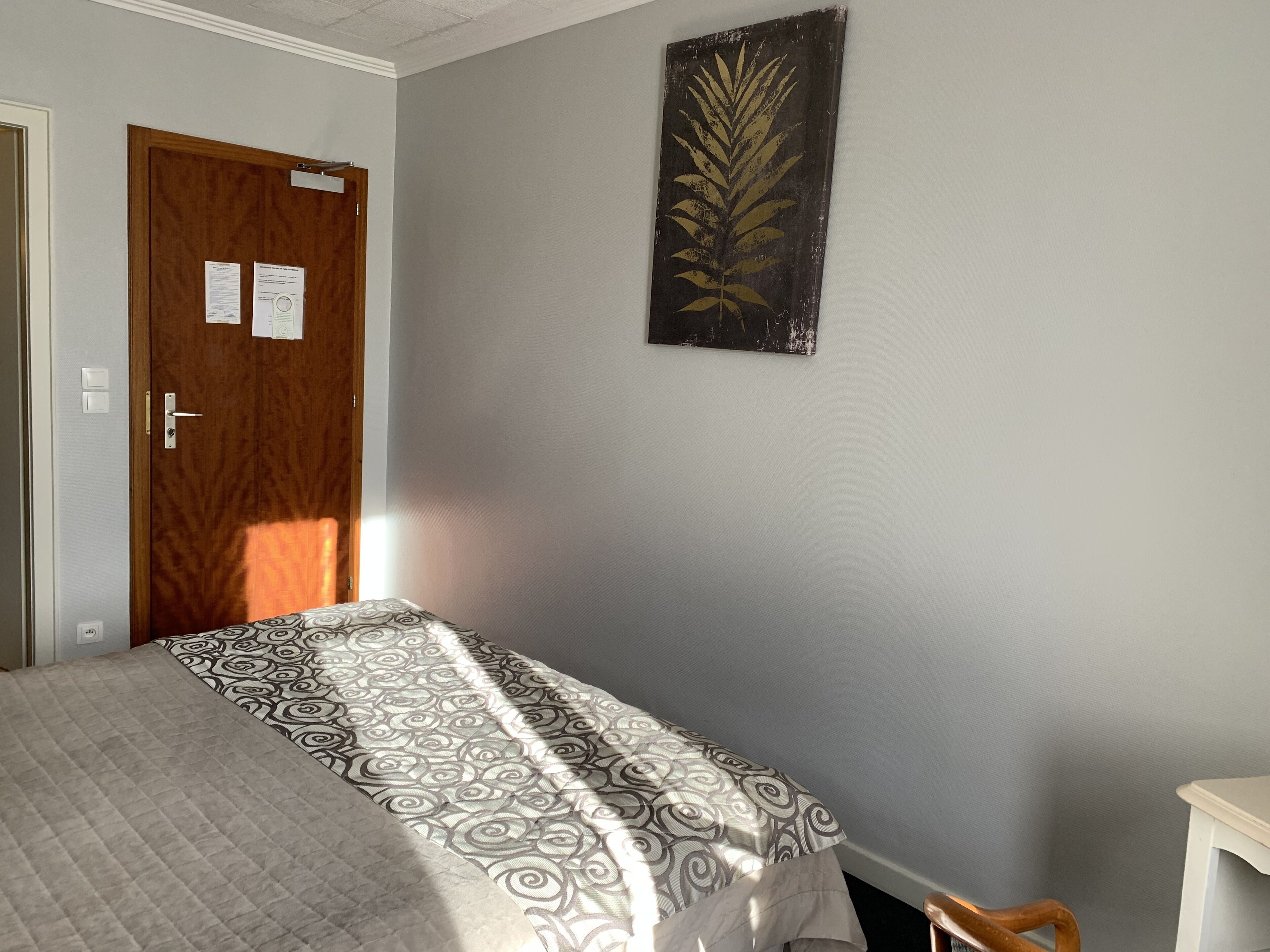 A bedroom with a bed, a wooden door, and a wall-mounted artwork.