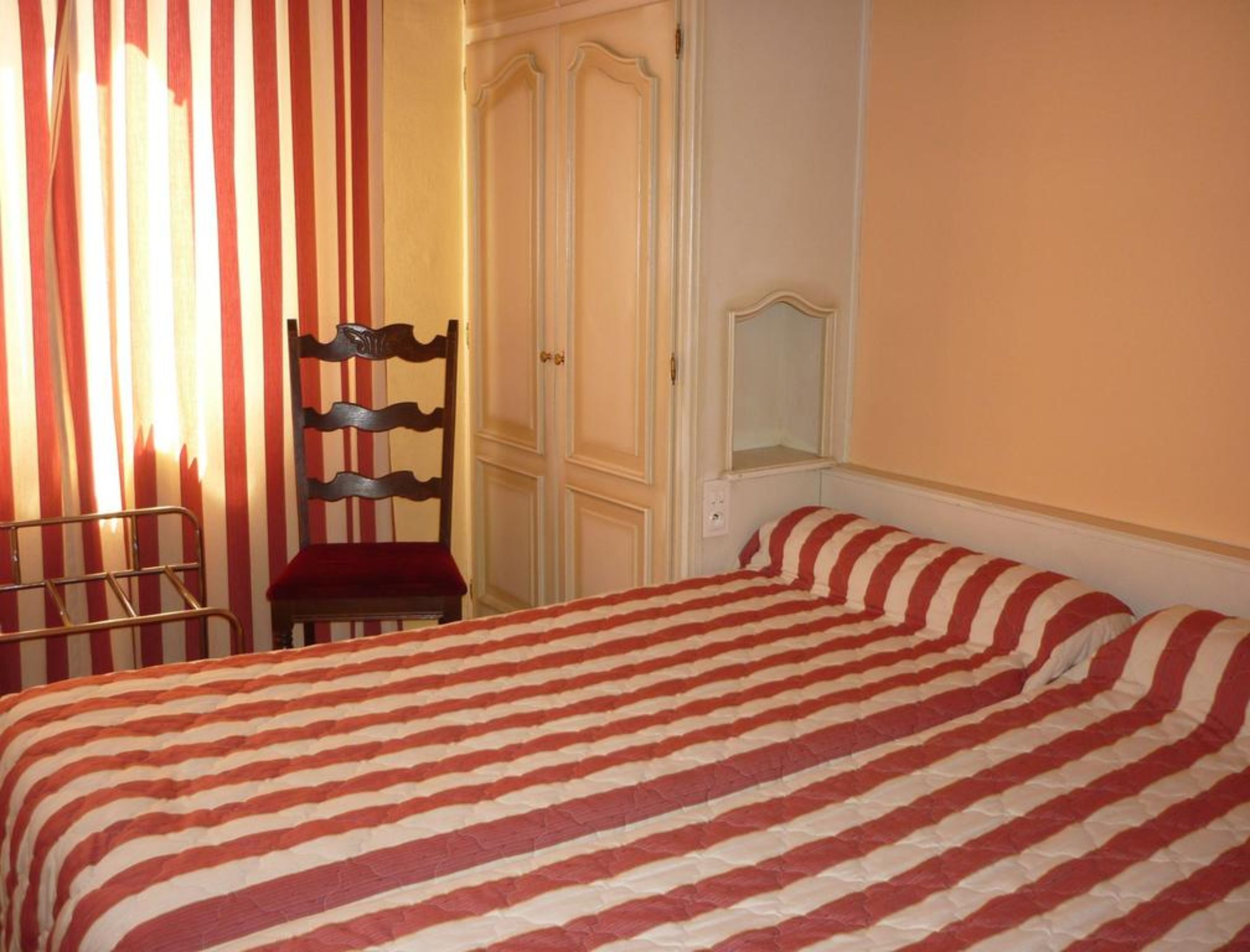 A bedroom with a bed, a chair, and a wardrobe.