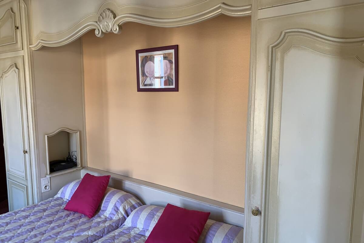 Un dormitorio con dos camas, cada una con ropa de cama a rayas y almohadas rojas. Encima de las camas hay un cuadro en la pared.