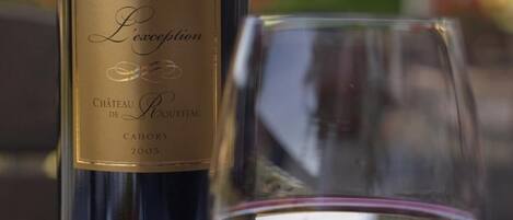 A bottle of L'Excellence wine with a label and a glass filled with red wine.