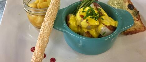 Un plato con un plato de huevos pochados, una rebanada de tostada y un recipiente pequeño de chutney.