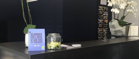 A reception desk with a sign reading "réception" and a glass jar with green plants.