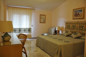 Ein Hotelzimmer mit einem Bett, einem Schreibtisch, einem Stuhl und einem Vorhangfenster.