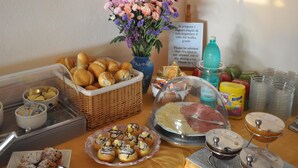 A buffet setup with various food items, including pastries, bread, and a variety of condiments. - L'Oasi (Dorgali)