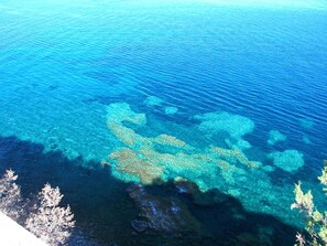 Ein klarer Blick auf eine Küstenlandschaft mit deutlich erkennbaren Felsformationen und blauem Wasser.