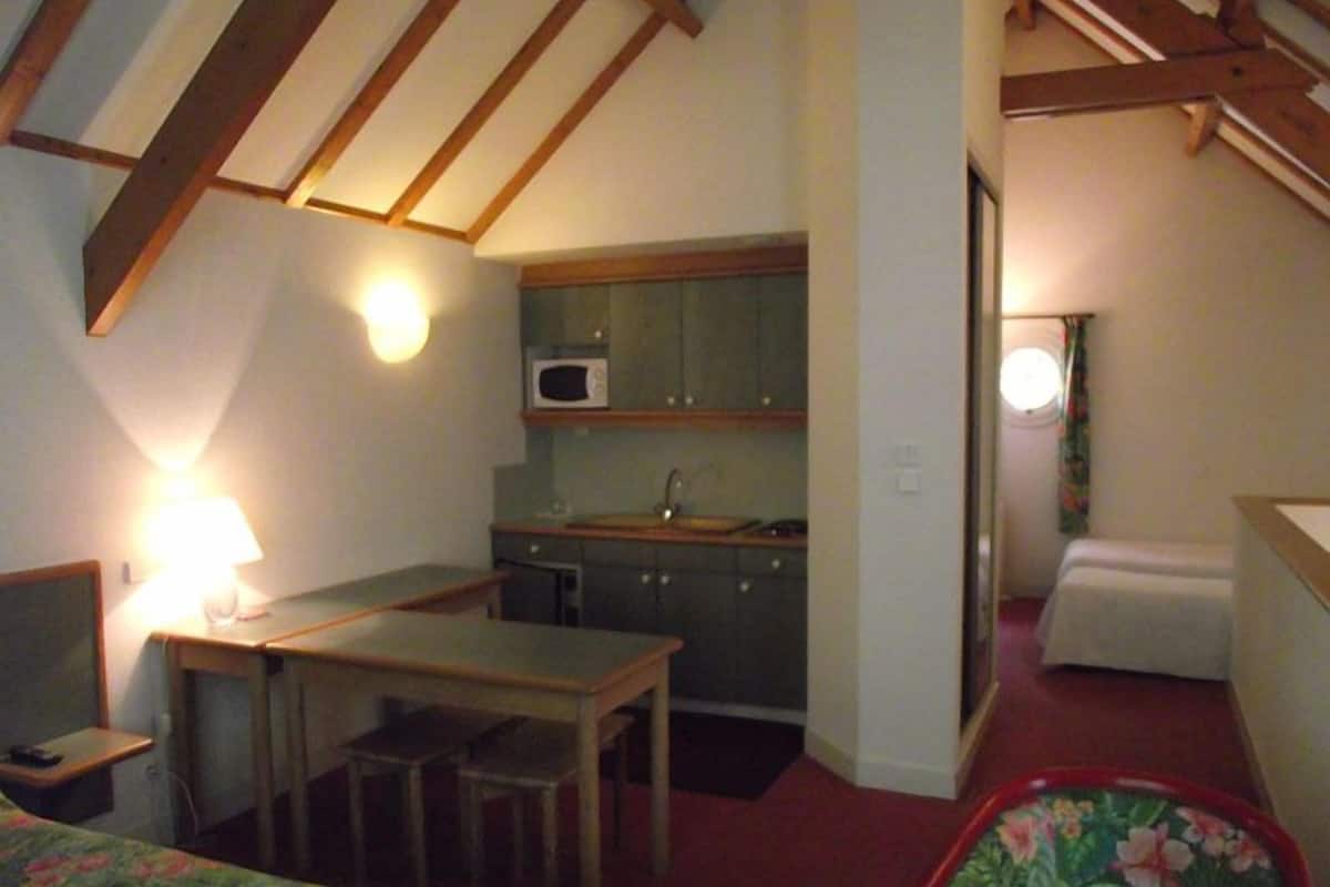 A compact room with a kitchenette, a bed, and a desk.