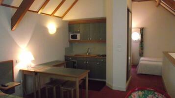 A compact room with a kitchenette, a bed, and a desk.