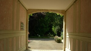 An arched doorway leading to a garden area with a paved path. - Citotel Avallon Vauban (Avallon)