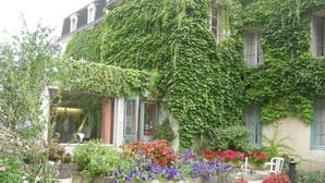 A building with a green ivy-covered exterior, stone planters with colorful flowers, and a reception area. - Citotel Avallon Vauban (Avallon)