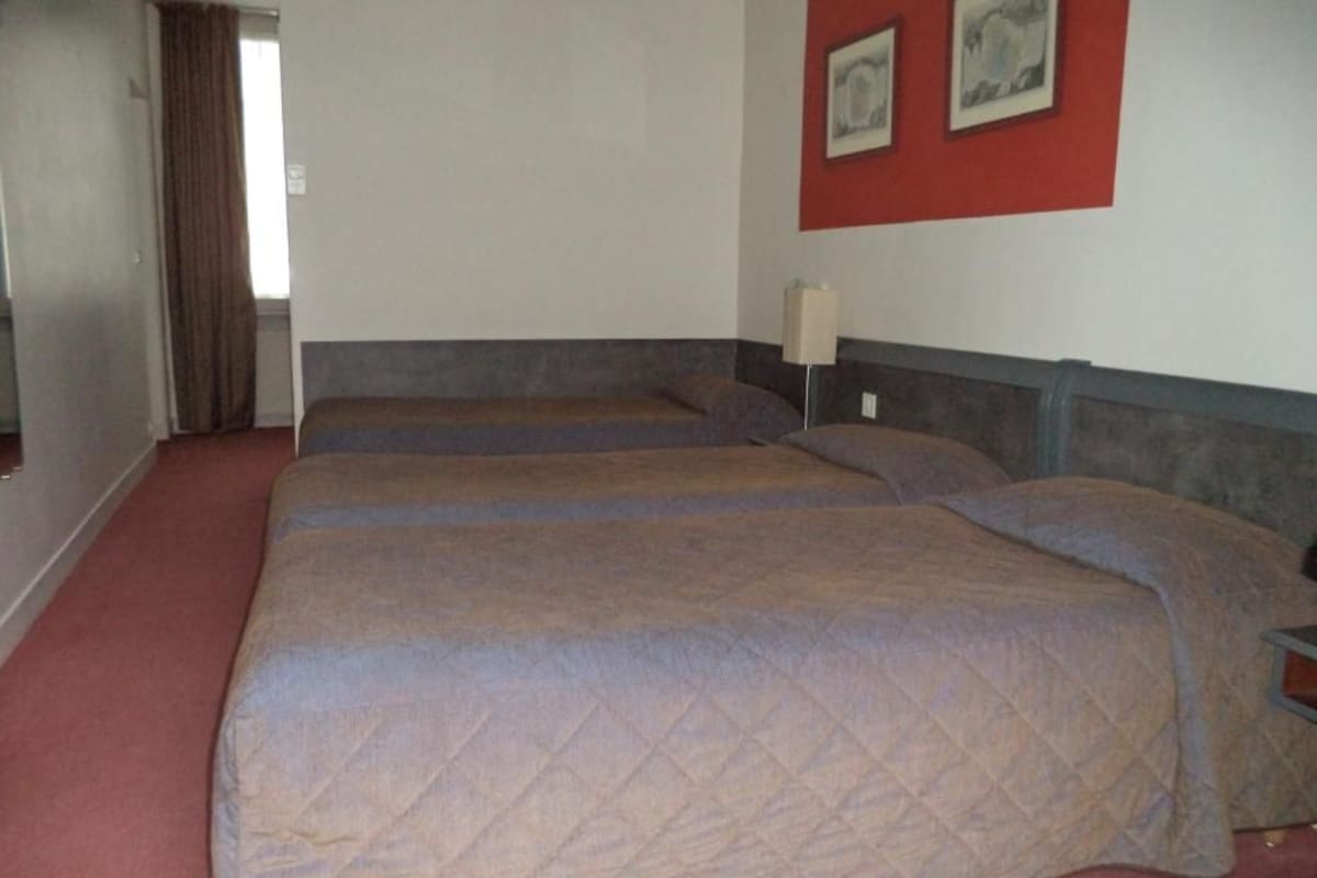 A hotel room with a large bed, a bedside table, and a lamp.
