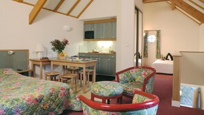 A bedroom with a bed, a desk, a chair, and a kitchenette. - Citotel Avallon Vauban (Avallon)