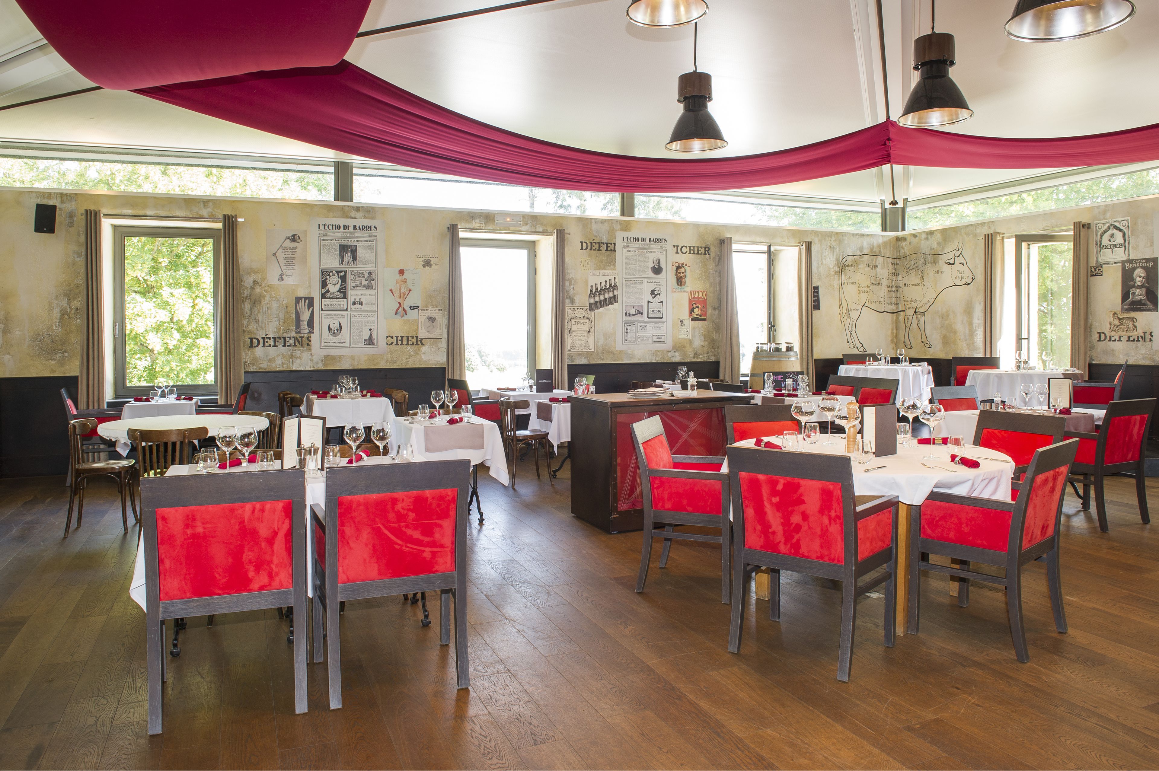 Un restaurante con mesas dispuestas para comer, sillas rojas y un cartel con el menú en la pared.