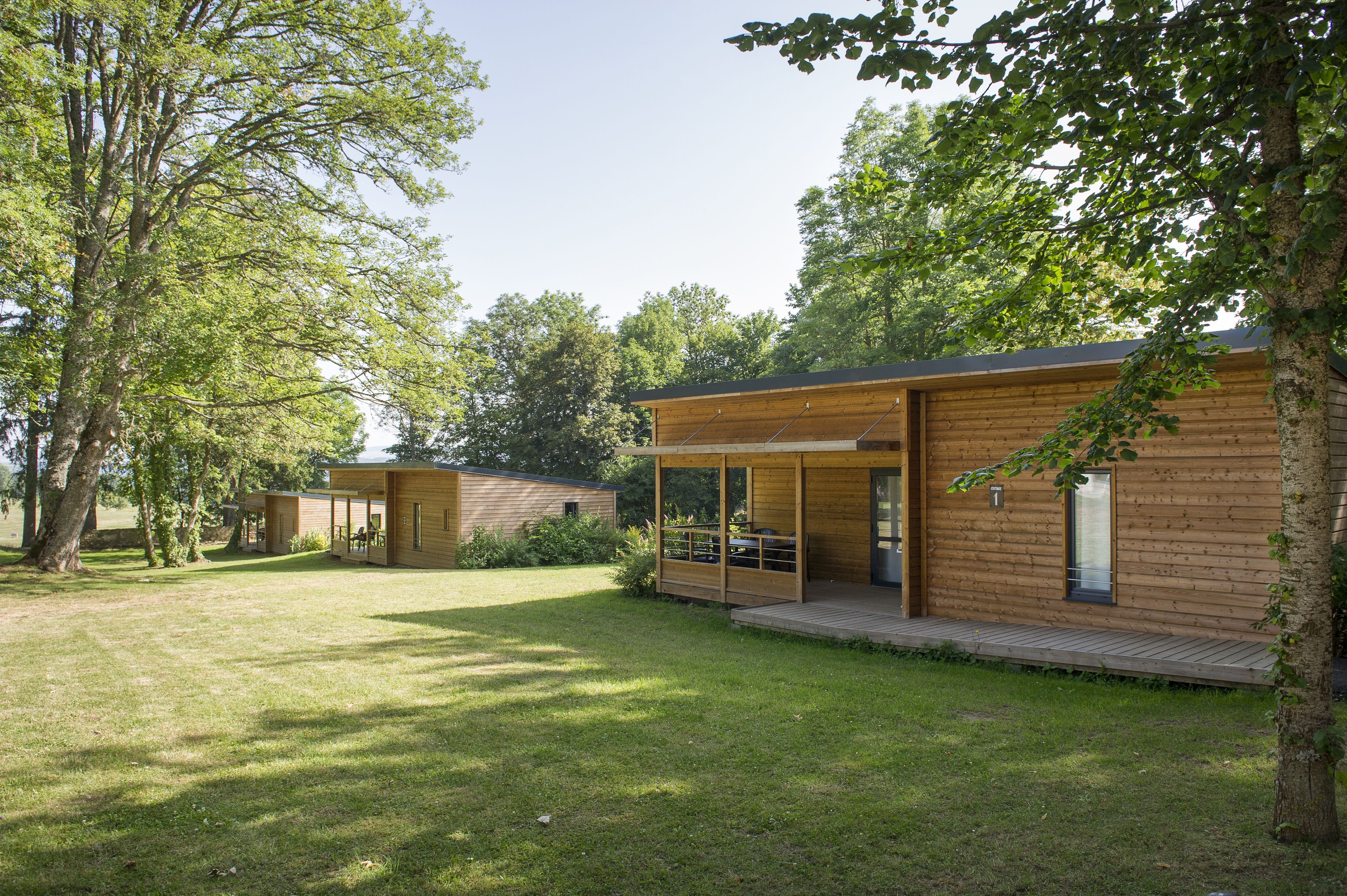 Una cabaña moderna de madera con terraza y zona de estar cubierta al aire libre.